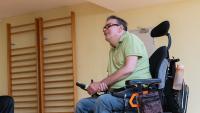 Two men in wheelchairs have discussion in gym.